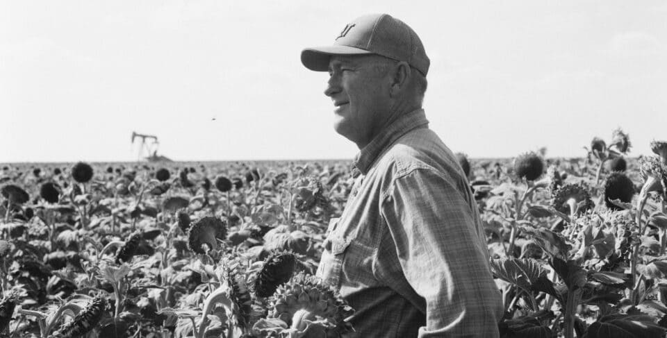 PLF client Cameron Edwards standing in a field looking off into the distance.