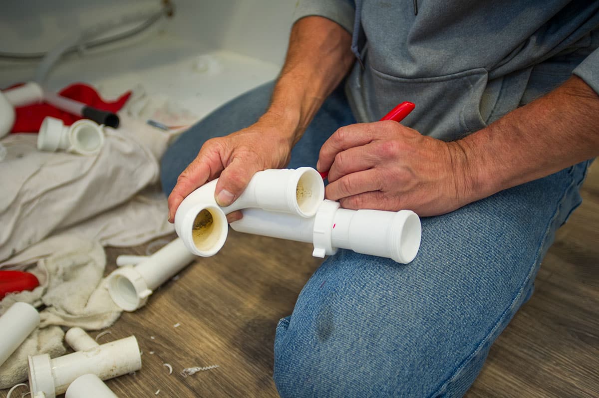 A plumber measures out his next cut on PVC pipe.