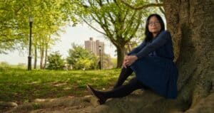 PLF client Yi Fang Chen sitting next to a tree.